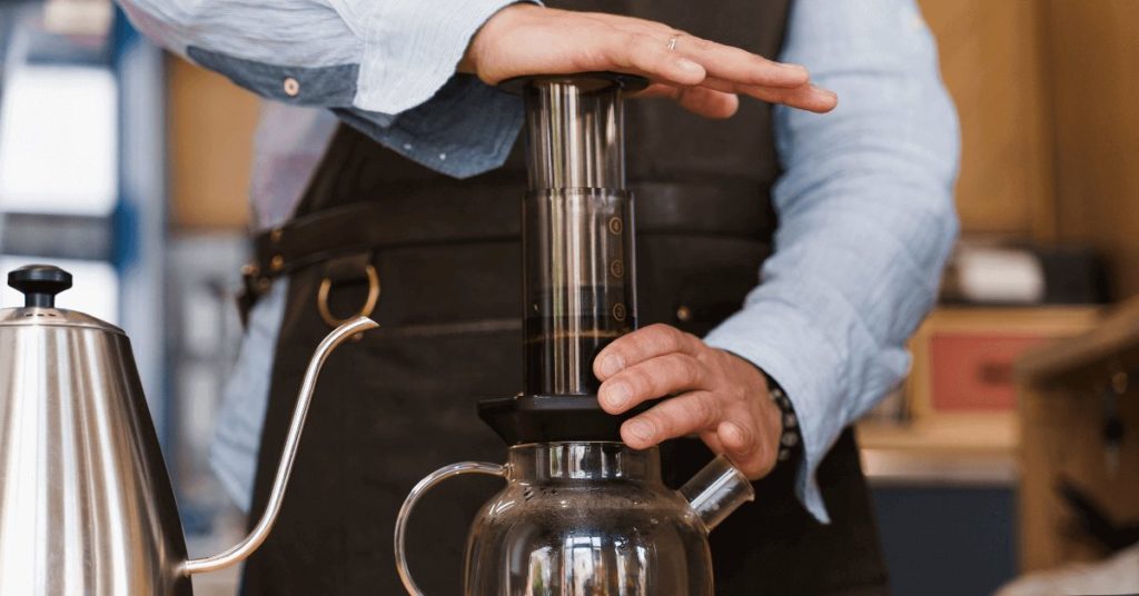 A person demonstrating the use of an AeroPress by pressing down the plunger