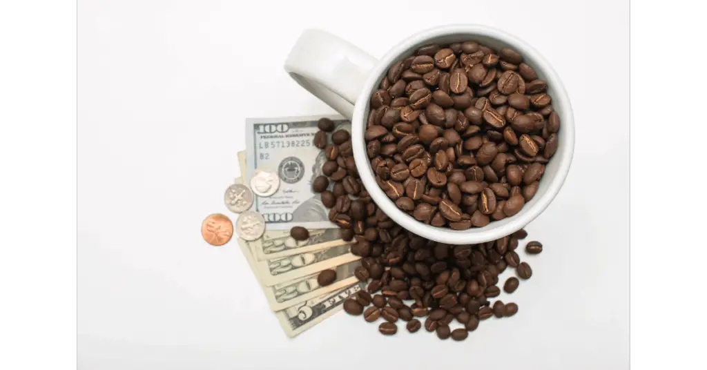A cup filled with coffee beans and sitting on a pile of money