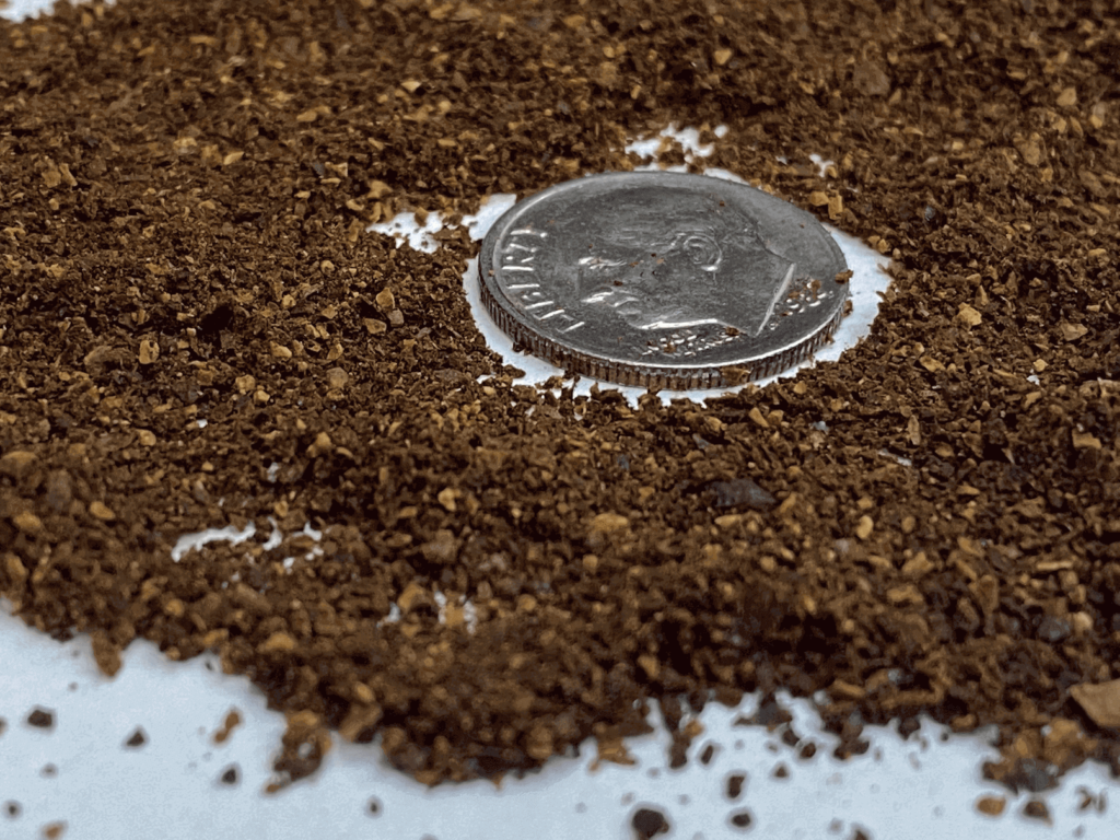 Medium-fine grind coffee, with a dime for size comparison