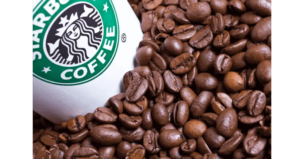 A starbucks cup surrounded by coffee beans, likely including some Sumatra coffee beans.