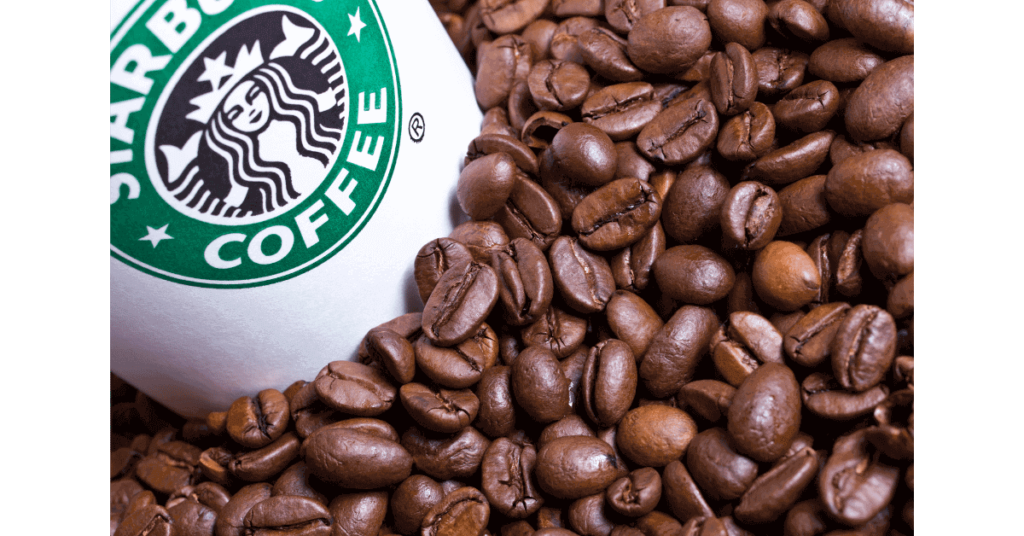 A starbucks cup surrounded by coffee beans, likely including some Sumatra coffee beans.