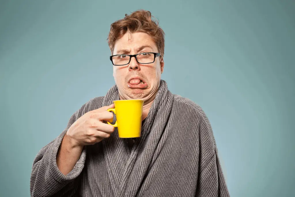 A person tasting bitter coffee from a coffee mug