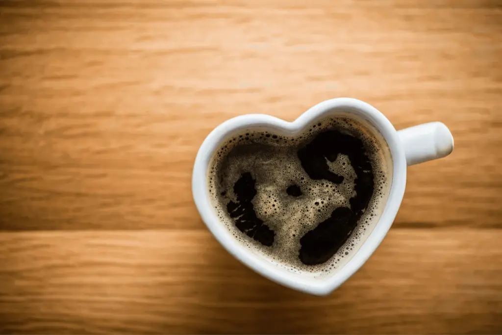 Black coffee in a heart-shaped mug, symbolizing the healthiness of the drink