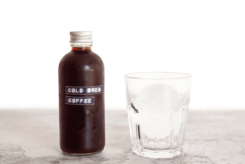 A bottle of pre-made cold brew coffee beside a glass of ice