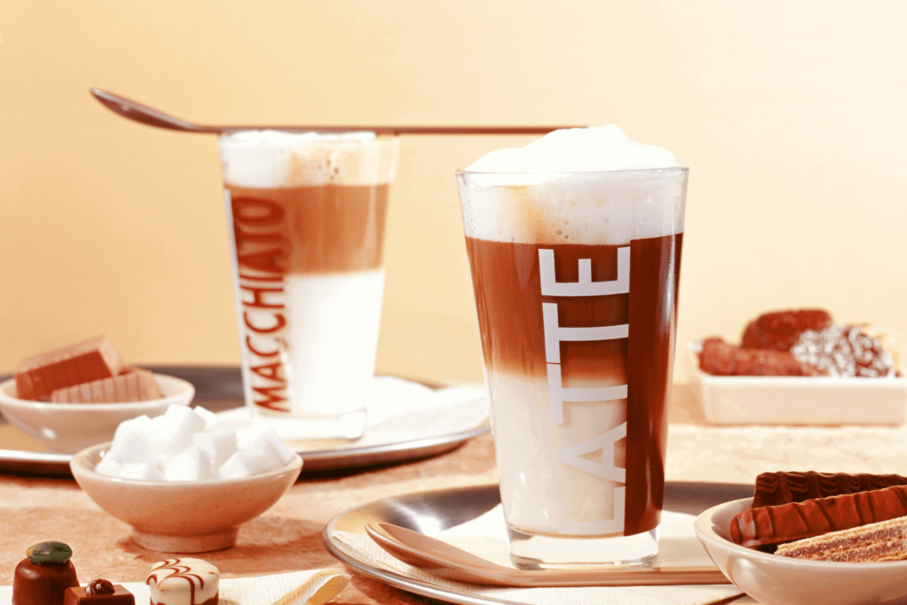 Two glasses of latte macchiato, showing the thick layer of milk below the splash of espresso