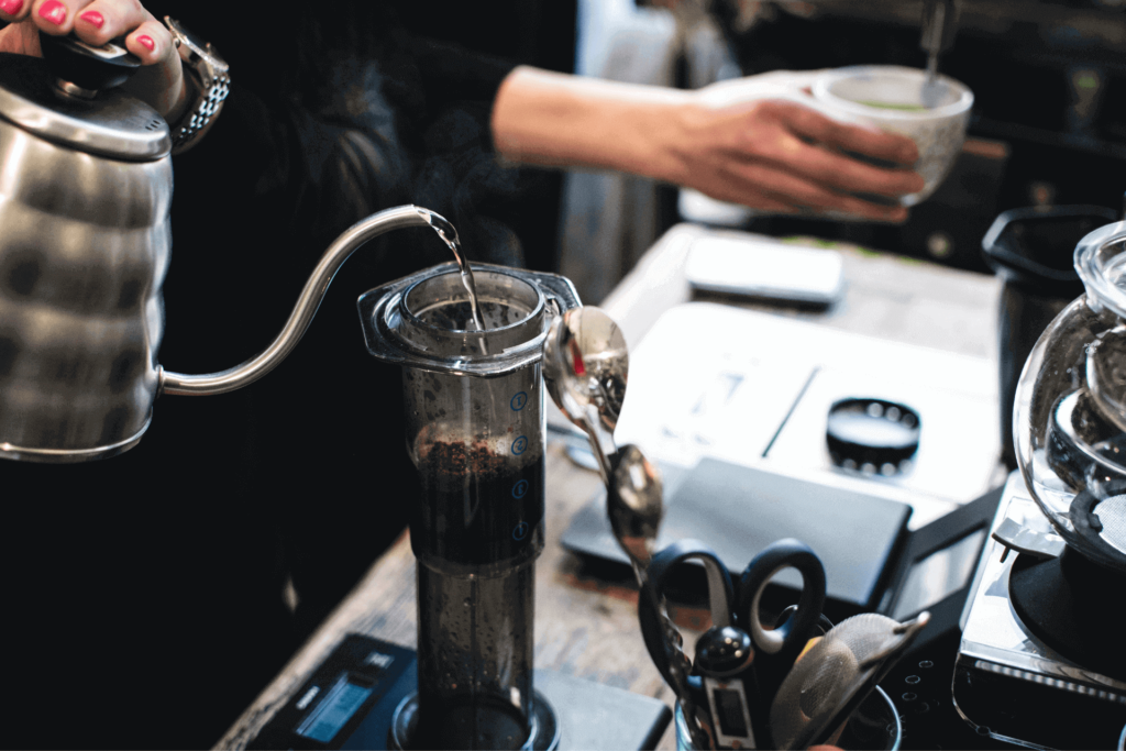 Pouring water into an inverted AeroPress coffee maker from a gooseneck kettle