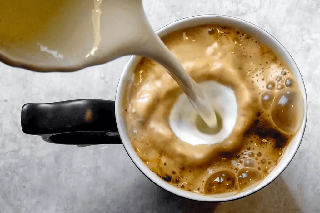 Pouring heavy cream in coffee, showing the rich change in texture