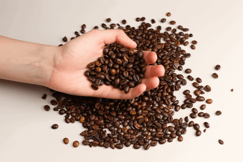 A hand holding coffee beans, like the beans you might use for French press cold brew coffee