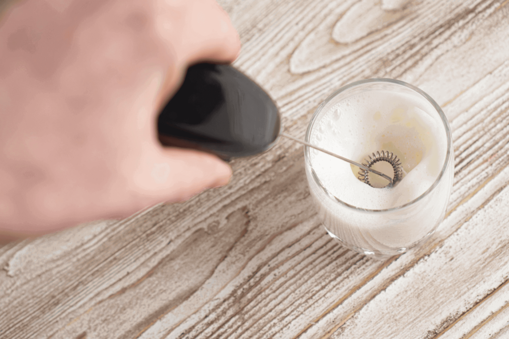 Using a handheld milk frother to prepare steamed milk for a latte