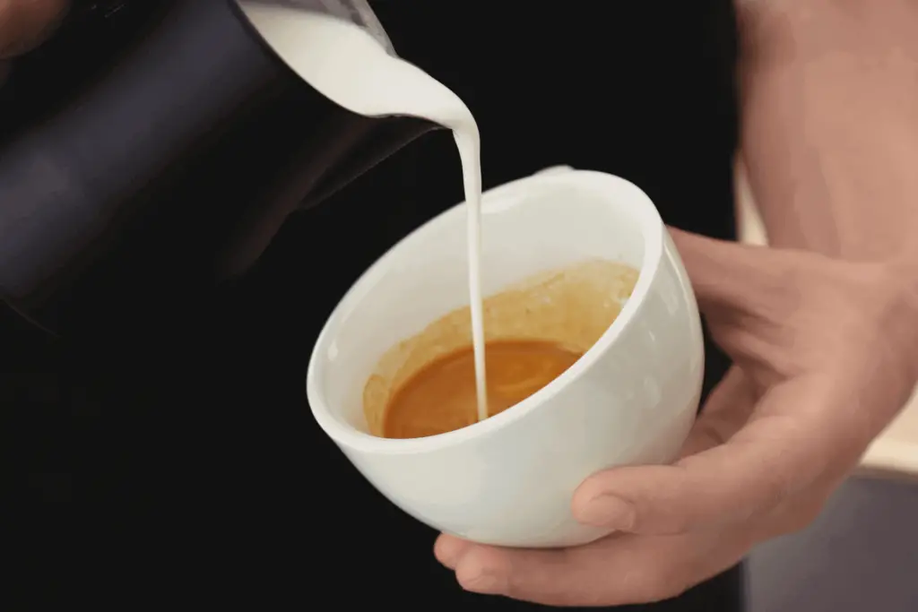 Pouring steamed milk into espresso to make a latte