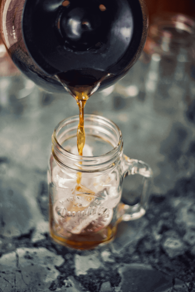 Pouring hot coffee over ice to make an iced coffee